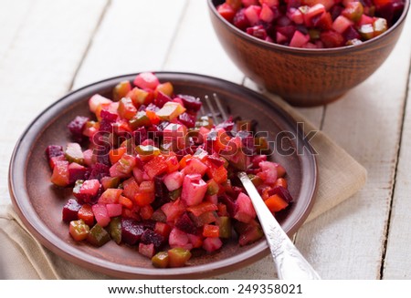 Traditional russian salad with beet, potato, carrot, cucumber on plate on white wooden table. Selective focus.