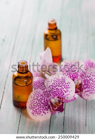 Extract of orxid flowers in bottle on aqua wooden background. Selective focus.