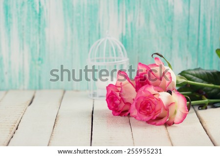 Background with fresh flowers. Roses on white wooden table. Selective focus is on right rose. Toned image.