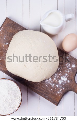 Dough on wooden board on white wooden background. Selective focus.