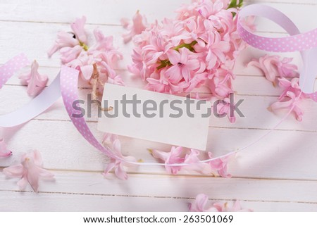 Postcard with fresh flowers hyacinths  and empty tag  on white painted wooden planks. Selective focus. Place for text.
