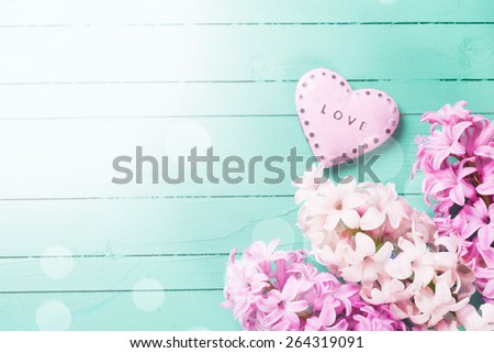 Postcard with fresh hyacinths  and  decorative heart with word love on it  on  green wooden background. Selective focus is on flowers. Place for text.