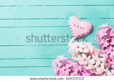 Postcard with fresh hyacinths  and  decorative heart with word love on it  on  wooden background. Selective focus is on flowers. Place for text.