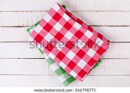 Bright red and green  kitchen towels on white painted wooden planks.