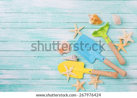 Garden tools for kids and sea object on turquoise  painted wooden planks. Place for text. Vacation background.