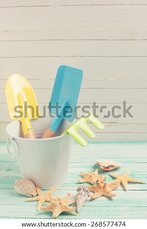 Tools for kids for playing in sand and sea objects on turquoise  painted wooden planks. Place for text. Vacation background. Toned image.