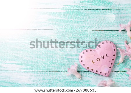 Postcard with little flowers hyacinths  and decorative heart  in ray of light on turquooie painted wooden planks. Selective focus. Place for text.