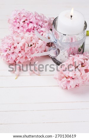 Background with white candle and fresh hyacinths flowers on white wooden background . Selective focus. Romantic background. Place for text.