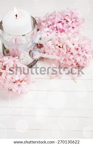 Background with white candle and fresh hyacinths flowers on white wooden background . Selective focus. Romantic background. Place for text. Toned image.