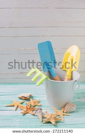 Tools for kids for playing in sand and sea objects on turquoise  painted wooden planks. Place for text. Vacation background.