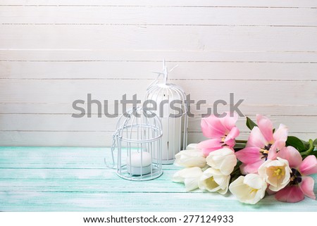 Background with fresh spring flowers and candles on turquoise painted planks against white wall. Selective focus. Place for text.