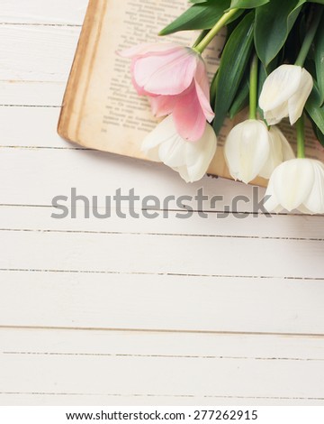 Fresh  spring white and pink  tulips on  vintage book on white  painted wooden background. Selective focus. Place for text.  Toned image.