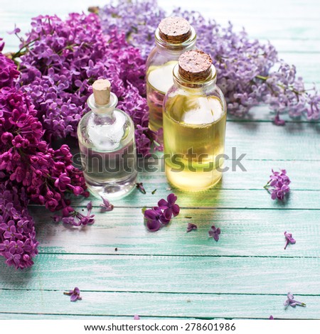 Essential aroma oil with lilac on  turquoise painted wooden background. Selective focus. Place for text. Square image.