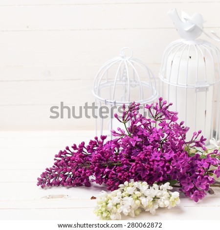 Fresh white and violet lilac flowers and candles on white painted wooden planks. Selective focus. Place for text.  Square image.