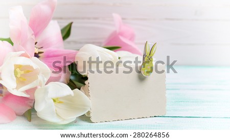 Postcard with fresh spring flowers and empty tag for your text on turquoise painted planks against white wall. Selective focus. Toned image.
