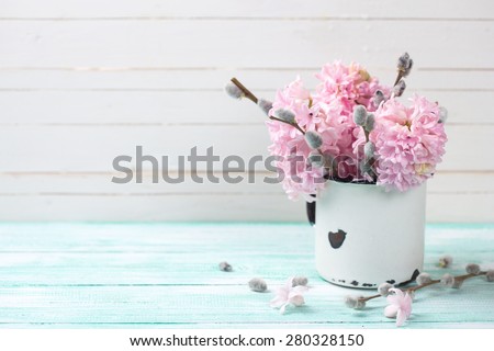 Background  with hyacinths and willow flowers  in aged mug on turquoise painted wooden planks against white wall. Selective focus and empty place  for your text.