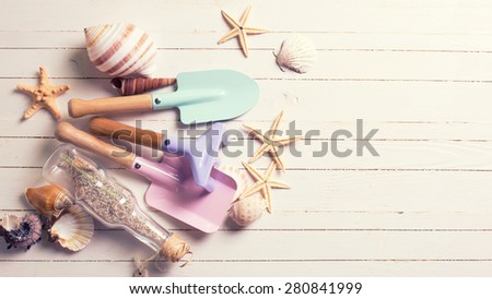 Tools for kids for playing in sand and sea object on white  painted wooden background. Place for text. Vacation background. Toned image.