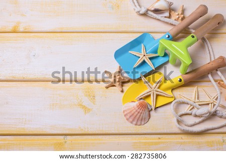 Tools for kids for playing in sand and sea object on  yellow  painted wooden background. Place for text. Vacation background.