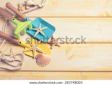 Tools for kids for playing in sand and sea object on  yellow  painted wooden background. Place for text. Vacation background. Toned image.