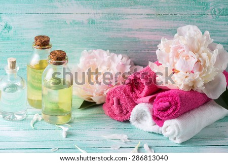 Spa setting. Essential aroma oil, towels, flowers on  turquoise painted wooden background. Selective focus.