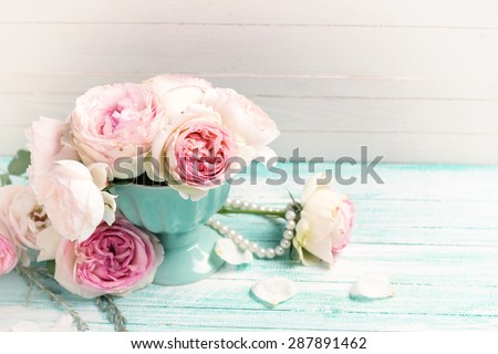 Background with sweet pink roses flowers  on turquoise painted wooden planks against white wall. Place for text. Selective focus. Toned image.