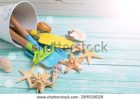 Tools for kids for playing in sand and sea objects in ray of light  on turquoise  painted wooden planks. Place for text. Vacation background.