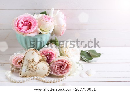 Background with sweet pink roses flowers  in ray of light on white painted wooden background against white wall. Selective focus. Place for text.