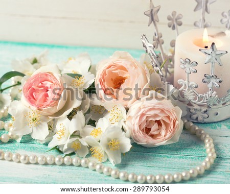 Sweet pastel  roses, jasmine flowers  and candle on turquoise wooden background. Place for text. Selective focus. Toned image.