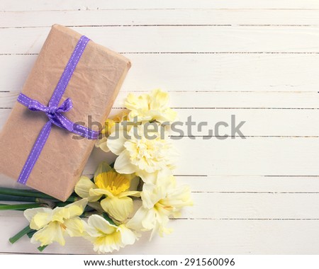 Spring flowers narcissus and box with present on white painted wooden planks. Selective focus. Place for text. Toned image.