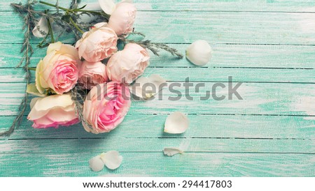 Fresh roses flowers on turquoise painted wooden background. Selective focus. Place for text. Toned image.