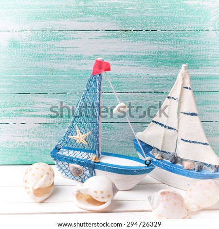 Decorative sailing boats and marine items on wooden background. Sea objects on wooden planks. Selective focus. Square image.