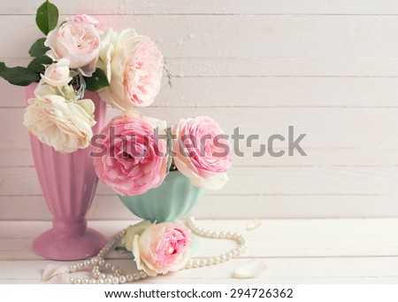 Sweet pink roses flowers in vases on white painted wooden background against white  wall. Selective focus. Place for text. Toned image.