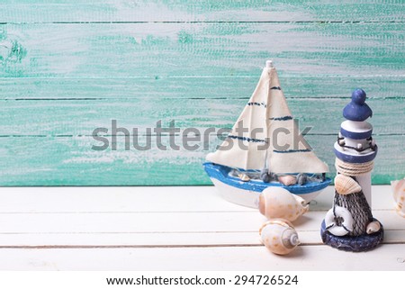 Decorative lighthouse,  sailing boats and marine items on wooden background. Sea objects on wooden planks. Selective focus. Place for text.