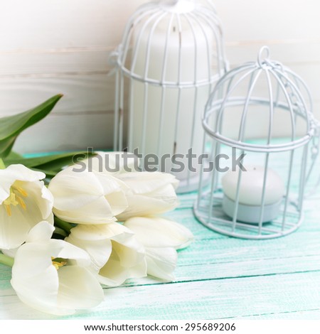 Background  with fresh spring white flowers and candles on turquoise painted planks against white wall. Selective focus. Square image.