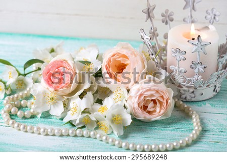 Sweet pastel  roses, jasmine flowers  and candle on turquoise wooden background. Place for text. Selective focus.