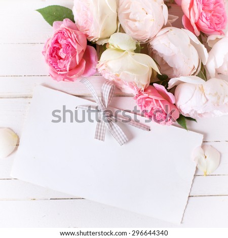 Sweet pastel roses  and empty tag  on white  wooden background. Place for text. Selective focus. Square image.