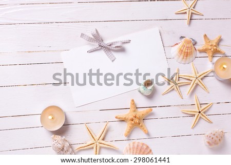 Marine items and candles  and tag for text on  white painted wooden background. Sea objects on wooden planks. Selective focus. Place for text.
