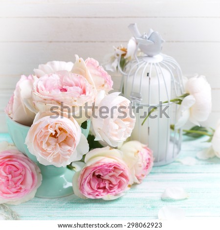Background with sweet pink roses in vase and candle  on turquoise painted wooden planks against white wall. Shabby chic.  Selective focus. Square image.