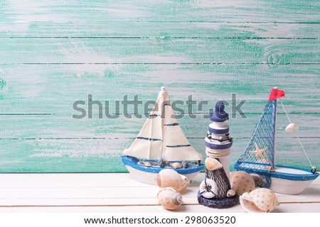 Decorative lighthouse,  sailing boats and marine items on wooden background. Sea objects on wooden planks. Selective focus. Place for text.