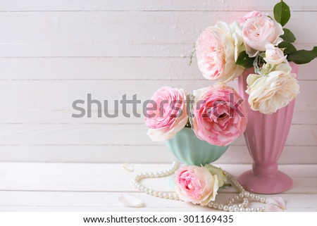 Sweet pink roses flowers in vases on white painted wooden background against white  wall. Selective focus. Place for text.