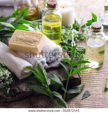 Wellness setting. Essential aroma oil, towels, soap on aged  wooden background. Selective focus. Square image.