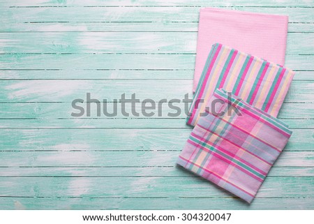 Pink  kitchen towels  on turquoise painted  wooden background. Selective focus. Place for text.