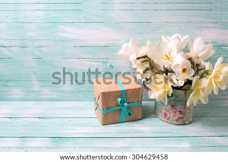 Background with colorful narcissus flowers and box with present  on turquoise painted wooden planks. Selective focus. Place for text.