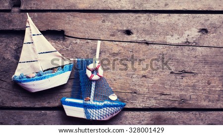 Decorative sailing boats on  vintage wooden background. Vacation background.  Selective focus. Place for text. Toned image.