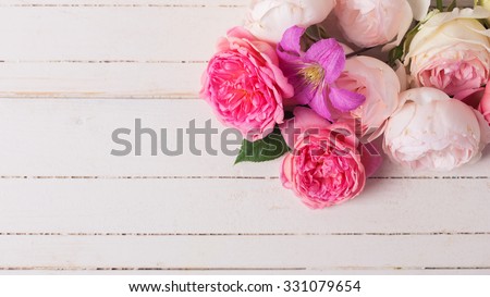 Sweet pastel roses and clematis flower on white  wooden background. Place for text. Selective focus. Toned image.