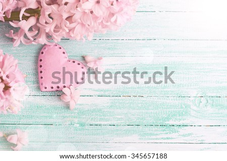 Background  with fresh flowers hyacinths  and decorative pink  heart in ray of light  on turquoise painted wooden planks. Selective focus is on heart. Place for text.