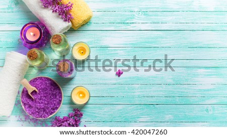 Spa setting. Sea salt in bowl, bottles with aroma oil,  towels and candles on turquoise  wooden background. Selective focus. Toned image.