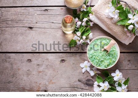 Border from spa products.  Sea salt in bowl, towels, aroma oil in bottles and flowers on  vintage  wooden background. Selective focus. Flat lay with copy space.