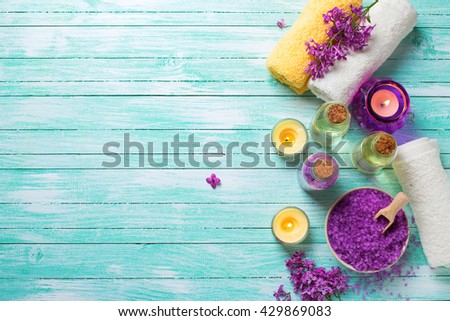 Spa setting. Sea salt in bowl, bottles with aroma oil,  towels and candles on turquoise  wooden background. Selective focus.