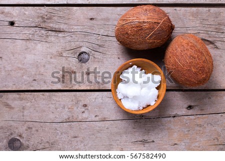 Coconuts oil in bowl  and coconut on  vintage wooden background. Selective focus is on oil. Natural organic spa products.